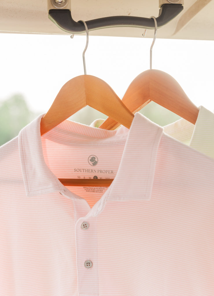 A lightweight Tensaw Stripe Polo hanging on a hanger