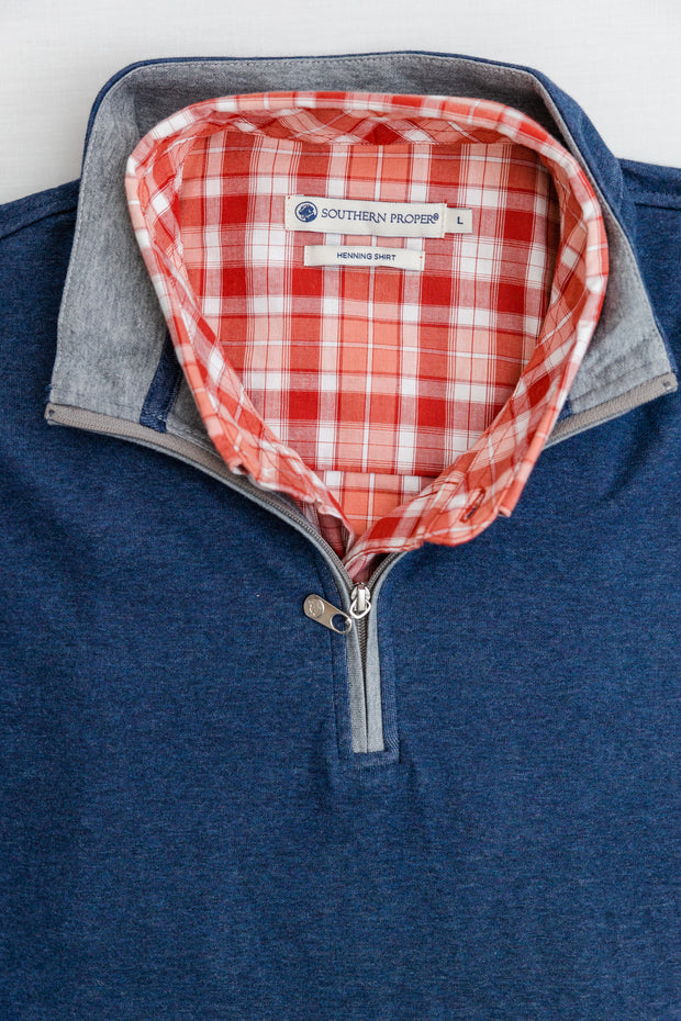 A close up of a blue Canal Quarter Zip with a red and white checkered pattern.