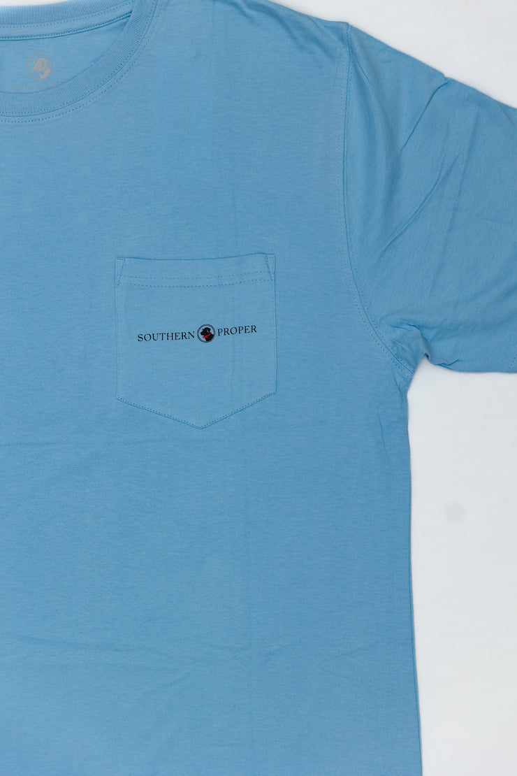 A light blue Southern Proper This Dog Hunts SS Tee with a logo on it.