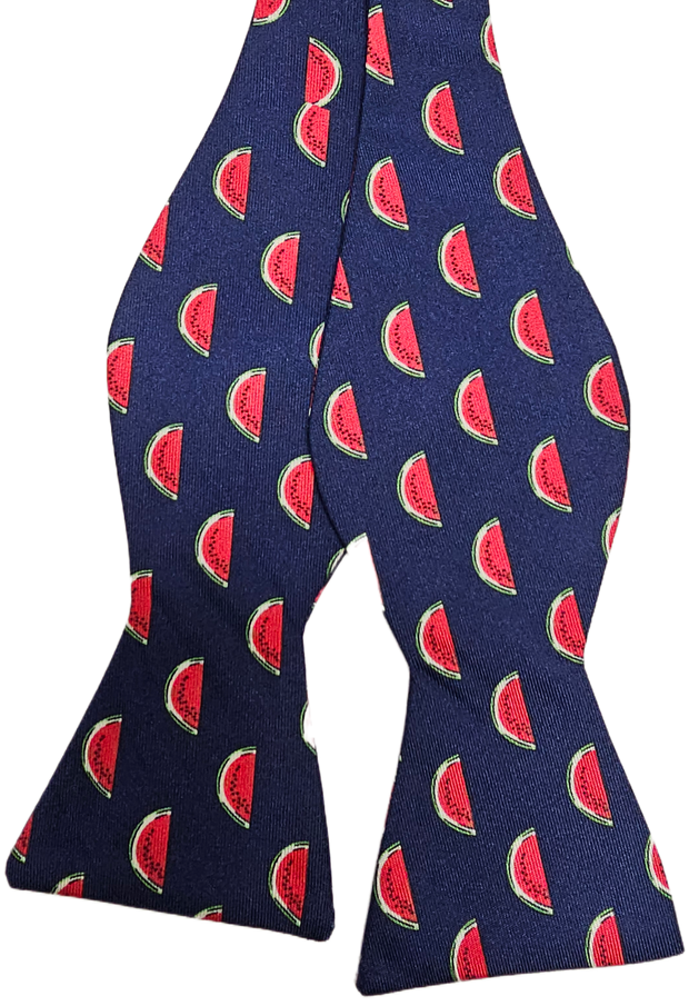 The Watermelon Bow: Navy is a navy hair accessory adorned with a playful pattern of red watermelon slices and green rinds.