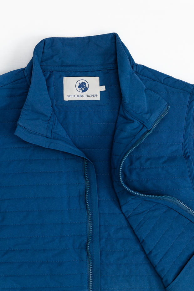 A Quilted Field Vest in a vibrant blue color, featuring a convenient zipper closure. Perfect for keeping warm during outdoor activities or layering for a stylish golf swing.