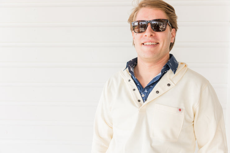 A man wearing sunglasses, sporting a relaxed fit Poydras Hoodie, in front of a white wall.