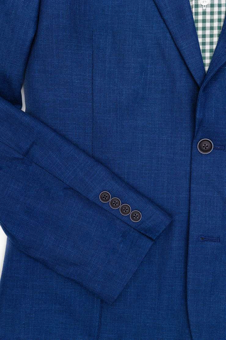 A classic unlined Nashville gentleman's jacket in a structure weave fabric. The suit features a blue color and contrast details, paired with a green checkered shirt.