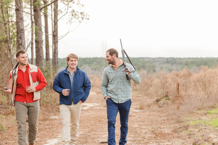 Three men wearing Thomasville Pants and tailored-fit clothing are walking down a trail with guns in their hands.