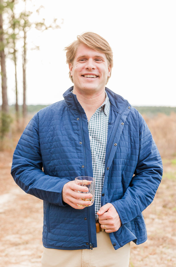 A versatile man in a Quilted Field Jacket holding a glass of wine.