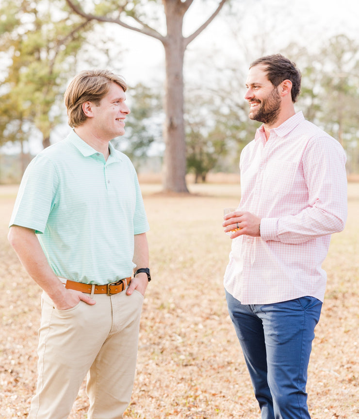 Two men standing in a field talking to each other while wearing Needle Creek Five Pocket Pant.