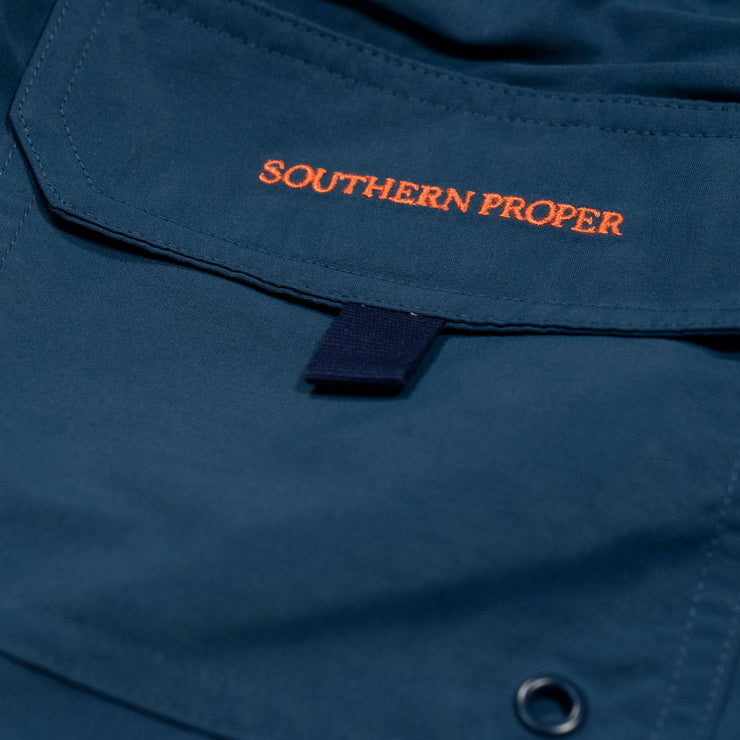 A close up of a blue Southern Swim 5.5" with the word "Southern Proper" on it, featuring an elastic waistband and nylon mesh liner.