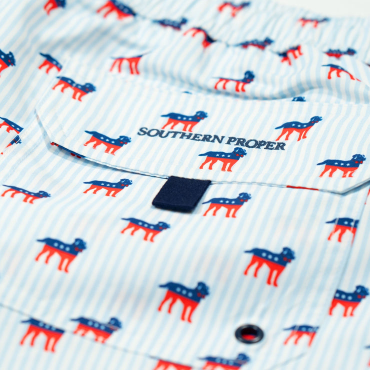 A pair of Southern Swim 7.5" swim trunks with red, white and blue dogs on them featuring an elastic waistband.