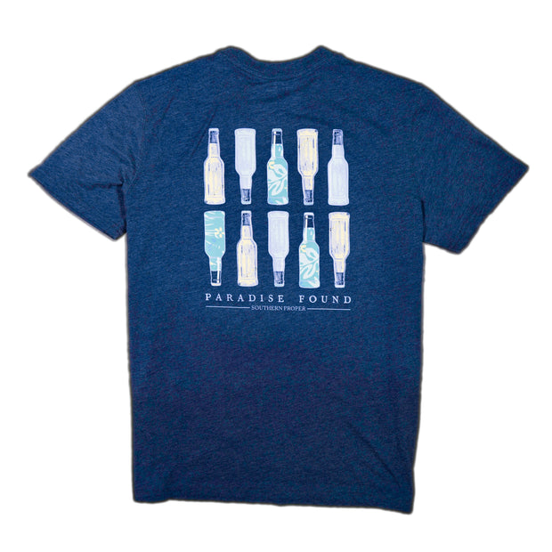 A Paradise Found SS Tee in blue with several bottles on it.